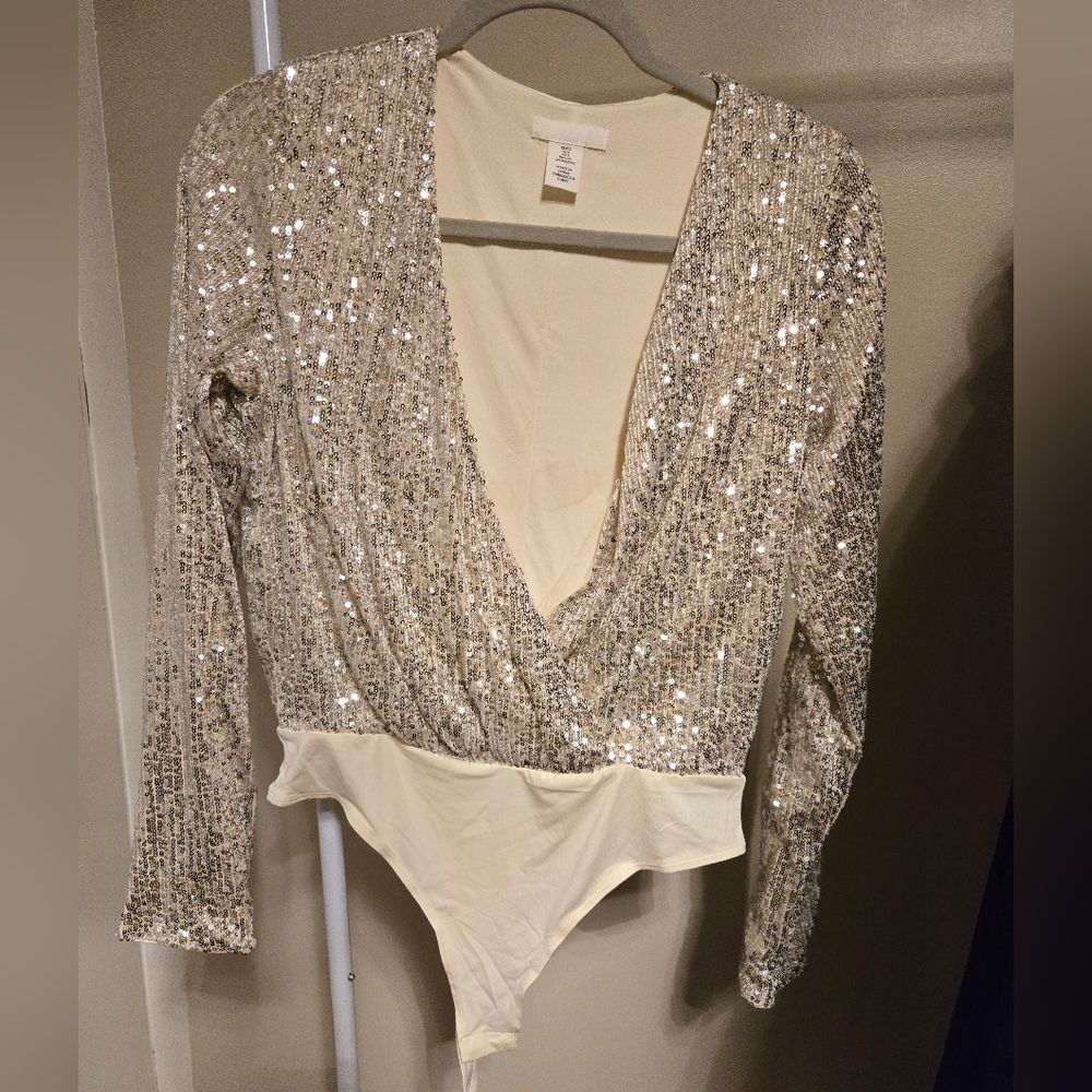 H&M body suit. Never worn, deep plunging neck. Silver sequined in size small